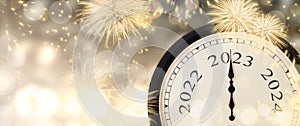 New Year 2023 clock and fireworks background.