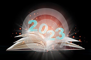 New year 2023 on open white paper fantasy book with shining pages isolated on black background