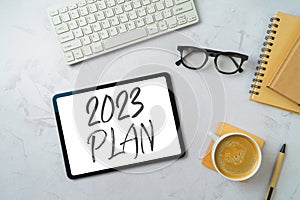 New Year 2023 plans and goals business concept with digital tablet, coffee cup and computer keyboard on modern office desk. Top