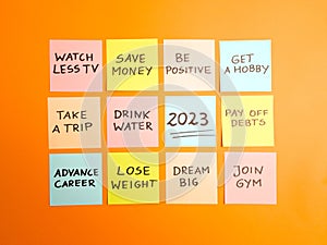 New Year 2023 resolutions handwritten on colorful sticky notes on orange background. Future planning, motivation, change and