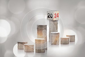 New year 2024 on cube on stack of coins on abstract background