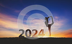 New year 2024 fitness healthy woman yoga with sunset sky background