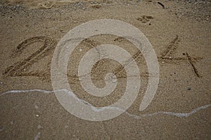 New Year 2024, lettering on the beach with wave and clear blue sea