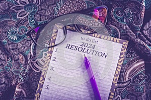 New year 2024 plan and resolution concept text on paper with purple pen and batik on background