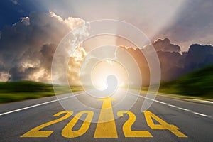 New year 2024 or straight forward concept. Text 2024 was written on the road in the middle of the asphalt road at sunset. Concept