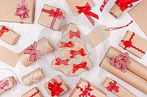 New Year background - various handmade kraft paper present boxes with bright red ribbons and bows on white wooden backdrop.