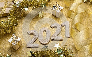 New Year card in gold colors. 2021 lettering decorated with ribbons and tinsel