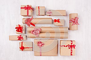 New Year celebration background - different kind craft paper gifts with red ribbons and bows on white wood plank, top view.