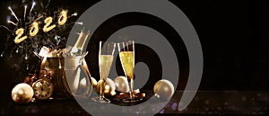 New year celebration banner with text 2020 champagne bottle and glasses, golden christmas decorations and fireworks against a dark