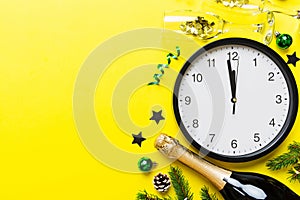 New year celebration concept with a bottle of champagne and two glasses toasting. Christmas gift box, alarm clock and