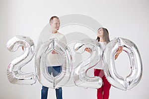 New year, celebration and holidays concept - love couple having fun with sign 2020 made of silver balloons for new year