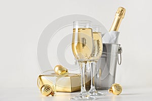 New Year champagne in wine glasses and bottle in bucket decorated Christmas gold baubles.