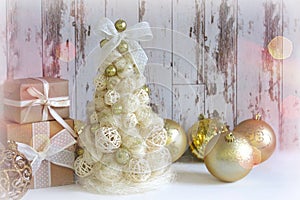 New Year, Christmas background, rustic style. Festive Christmas tree in gold on white wood background and craft boxes tied with sa