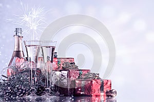 New Year and Christmas celebration. Champagne, two wine glasses, fireworks and gifts on blinking holiday background.