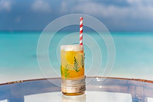 New year and christmas celebration theme cocktail with straw and pine leaves on the glass on the beach