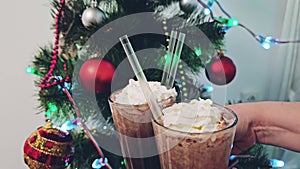 New Year Christmas clatter glasses of hot chocolate cocoa with cream and straws Christmas tree bright red toys lights