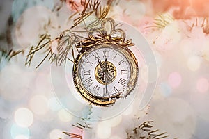 New year and Christmas clock lying on a snow under a fir tree in the forest