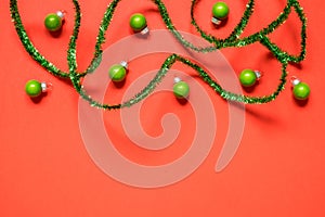 New Year or Christmas composition 2021. Top view xmas decorative red paper background with green tinsel and Christmas decorations