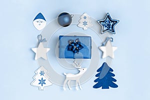 New Year and Christmas composition from christmas toys and gift box on blue background. Top view, flat lay. Trendy color of the