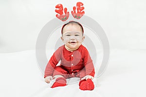 New year and Christmas concept with 5 months old cute newborn baby boy wearing christmas antlers of a deer,red clothes sitting on