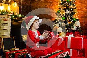 New year Christmas concept. Happy little child dressed in winter clothing think about Santa near Christmas tree