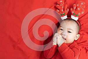 New year and Christmas concept.Headshot of 5 months old cute newborn baby boy wearing christmas antlers of a deer on a red blanket