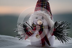 New Year Christmas concept. The snowman stands on snow with blurred nature background. White snowman surrounded by Christmas trees