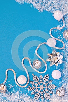 New year and Christmas decor in white and silver colors: balls, snowflake, bow, ribbon on a blue background under the