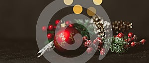 New Year and Christmas decoration, holiday background. Red festive ball bauble, green fir xmas tree and yellow blurred lights.