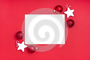 New Year and Christmas frame composition. Blank sheet of paper with christmas decorations on red background. Top view, flat lay,