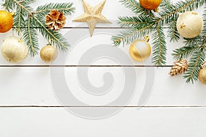 New year or Christmas golden decorations and fir tree branches on white wooden background. Flat lay, top view, copy space.