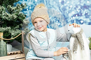 New year and Christmas. Little boy sitting with soft toy penguin on winter decorated background