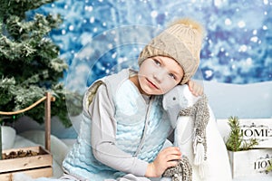 New year and Christmas. Little boy sitting with soft toy penguin on winter decorated background