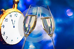 New Year or Christmas at midnight with champagne flutes make cheers blue bokeh and clock