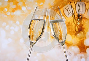 New Year or Christmas at midnight with champagne flutes make cheers, golden bokeh and clock