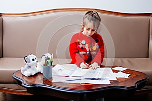 New year christmas pensil little girl writes letter Santa red jacket toy pen kid table sofa