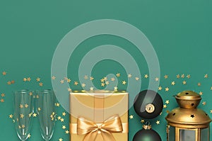 New Year Christmas presents, Christmas balls, champagne glasses, gold confetti stars on green background top view. Flat