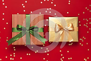 New Year Christmas presents with green ribbon, golden gift, confetti stars on red background top view. Flat lay Xmas holiday 2020