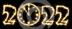 New Year 2022 with clock made by sparkler . Number 2022 and sign written sparkling sparklers . Isolated on a black background .
