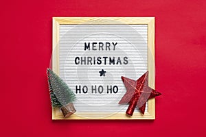 New Year composition of star, tree, white felt board with text Merry Christmas, ho ho ho on red background Holiday card Xmas