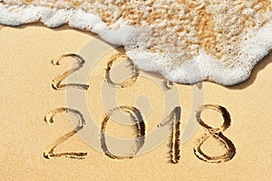 New Year concept - 2017 and 2018 handwritten in the sandy beach