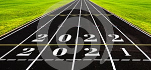 New year concept with black rubber running track with numbers, ideas of overcome year 2021 to coming year 2022. Start of racing,