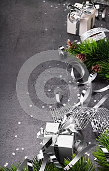 New Year concept. Bright christmas gift with silver ribbon close up, fir tree and confetti