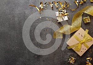 New Year concept. Bright gifts with gold ribbon, streamer and confetti on dark. Space for text. Top view