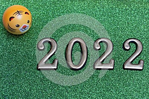 New year concept: golden numbers 2022 with tiger face on green glitter background with copy space