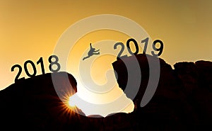 New year concept, silhouette a man jumping across cliff from 2018 to 2019