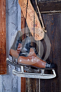 New Year concept of vintage hockey skates hanging on a wooden wall next to a sign saying Welcome