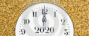 New year countdown, midnight clock face on a shiny yellow gold glitter textured background, web banner
