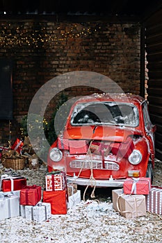 New Year decorated exterior with trunk full of Christmas gifts of retro red car with snow and festive lights and