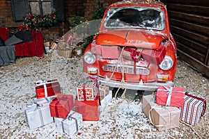 New Year decorated exterior with trunk full of Christmas gifts of retro red car with snow and festive lights and